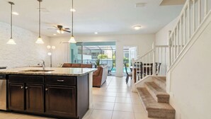 A modern kitchen with a central island, dark cabinetry, and pendant lighting. - 5-br Townhouse With Pool, Games, Disney (Kissimmee)