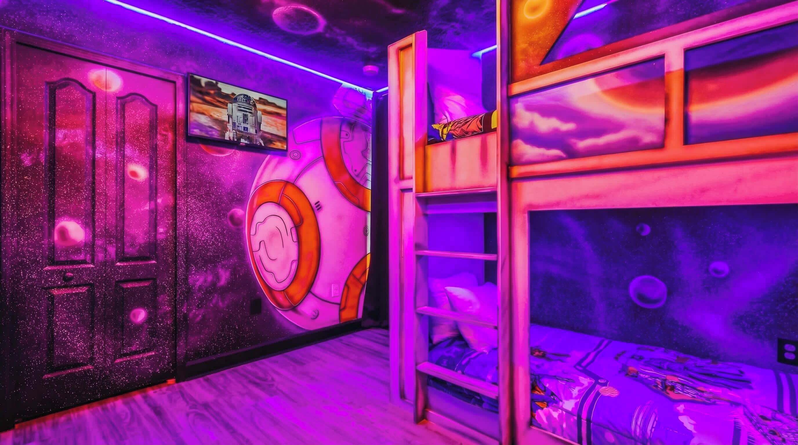 Een kamer met een stapelbed, een muur met een ruimtetema-muurschildering, en een deur met een rond ontwerp.