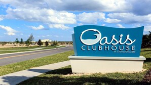 Schild für den Oasis Clubhouse in ChampionsGate, mit freier Straße und Grün im Hintergrund.