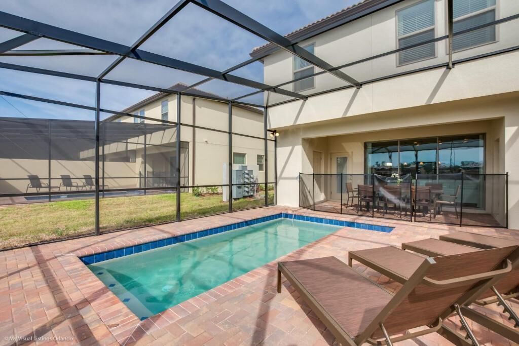 A pool area with a glass enclosure, outdoor seating, and a view of the surrounding landscape.