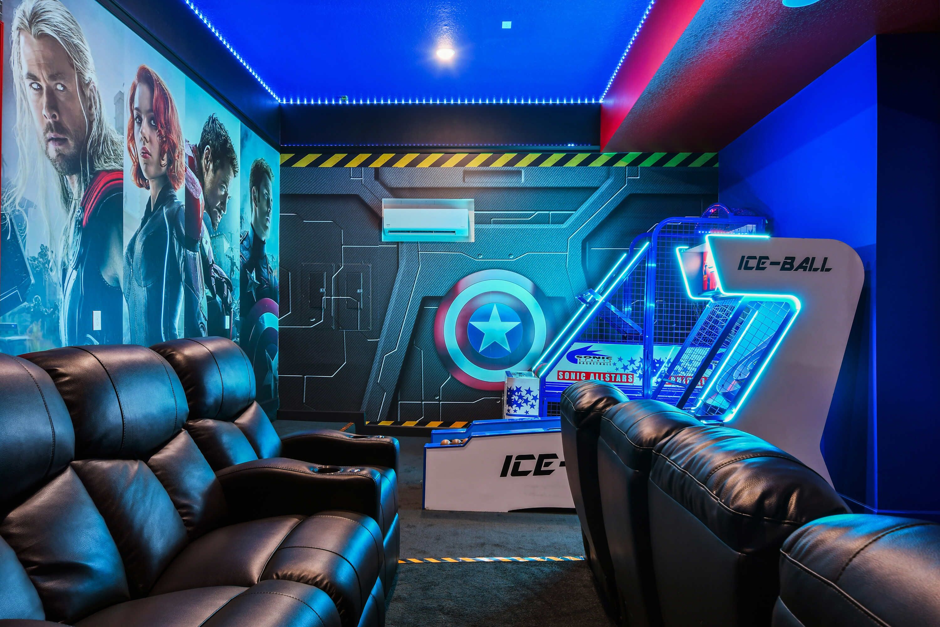 A room with leather seating, a wall-mounted gaming console, and a Captain America poster.