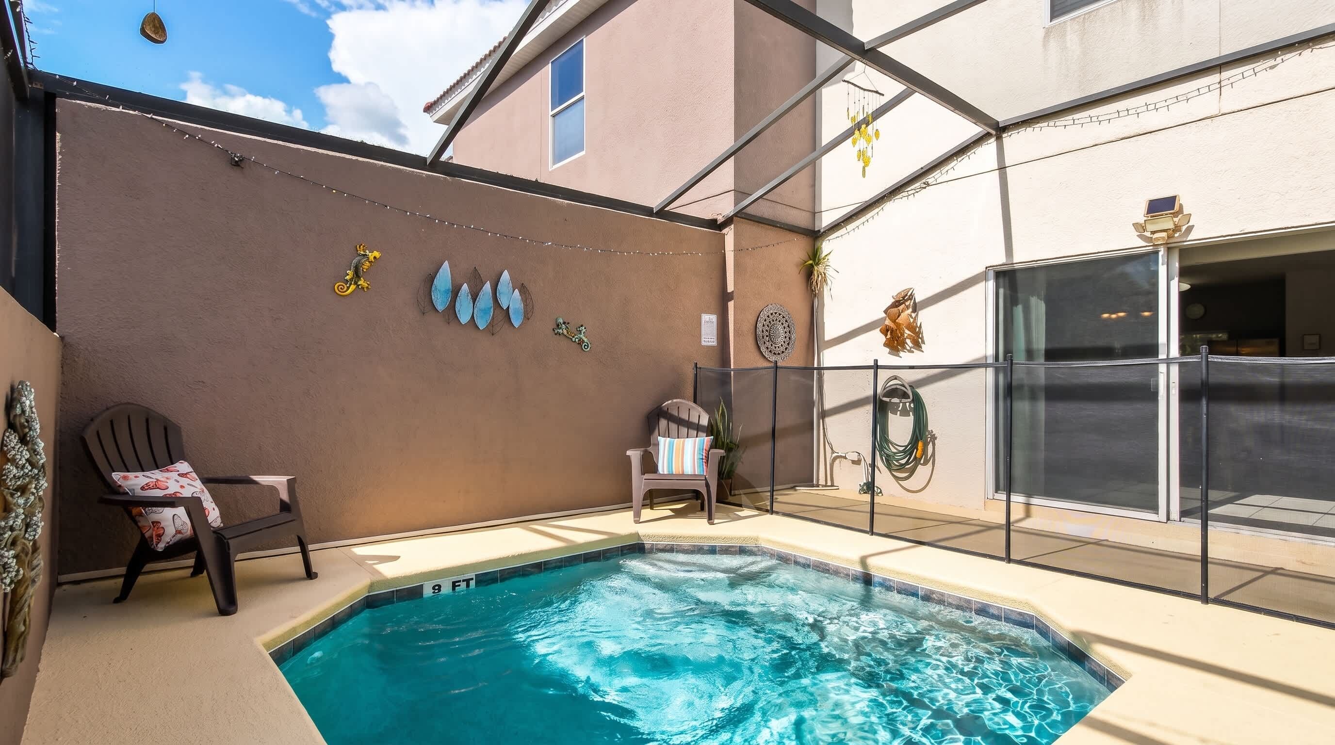 Une piscine dont la profondeur maximale est indiquée à 9 pieds, une chaise avec un coussin à motifs et un mur décoratif orné de divers objets.