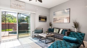 A modern living room with a sofa, armchairs, and a coffee table. There is a sliding glass door leading to a pool area. - 3-bedroom Villa in Bella Vida Resort, Close2disney (Kissimmee)