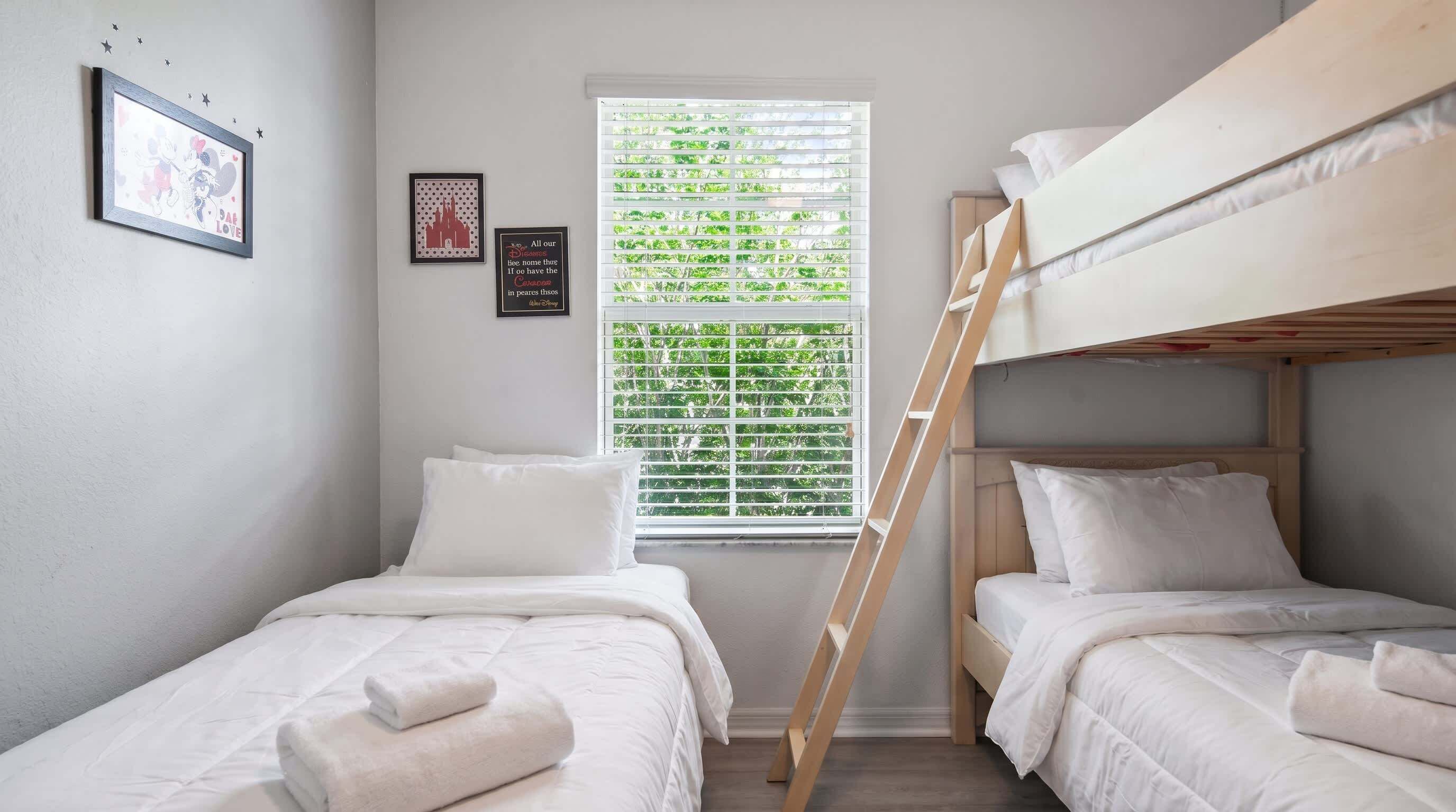 Een kamer met stapelbedden, een raam met jaloezieën en wanddecoraties.