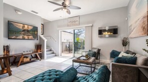 A modern living room with a fireplace, a staircase leading to a balcony, and a large window. - 3-bedroom Villa in Bella Vida Resort, Close2disney (Kissimmee)
