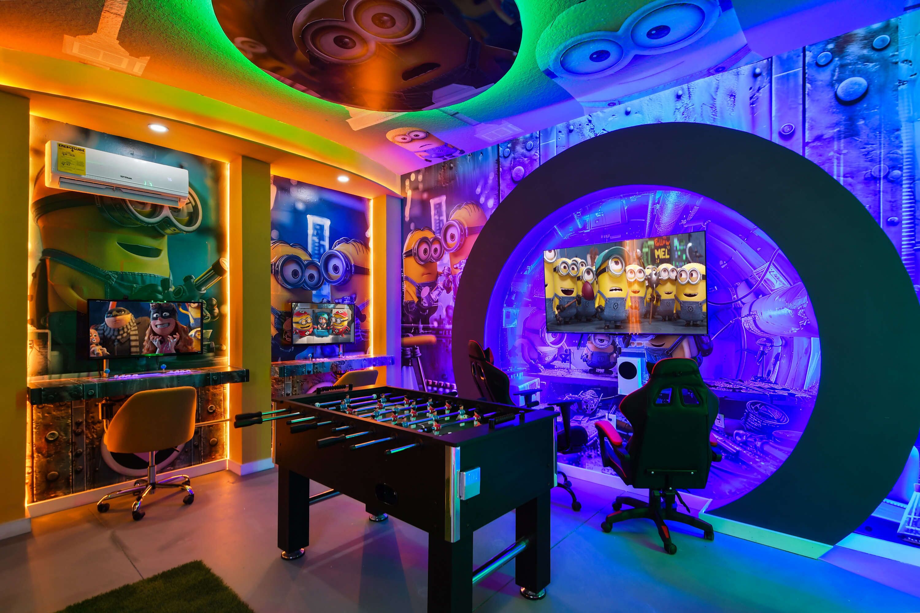 Ein Zimmer mit Kicker, Gaming-Stuhl und einem großen Bildschirm, der einen Film zeigt.