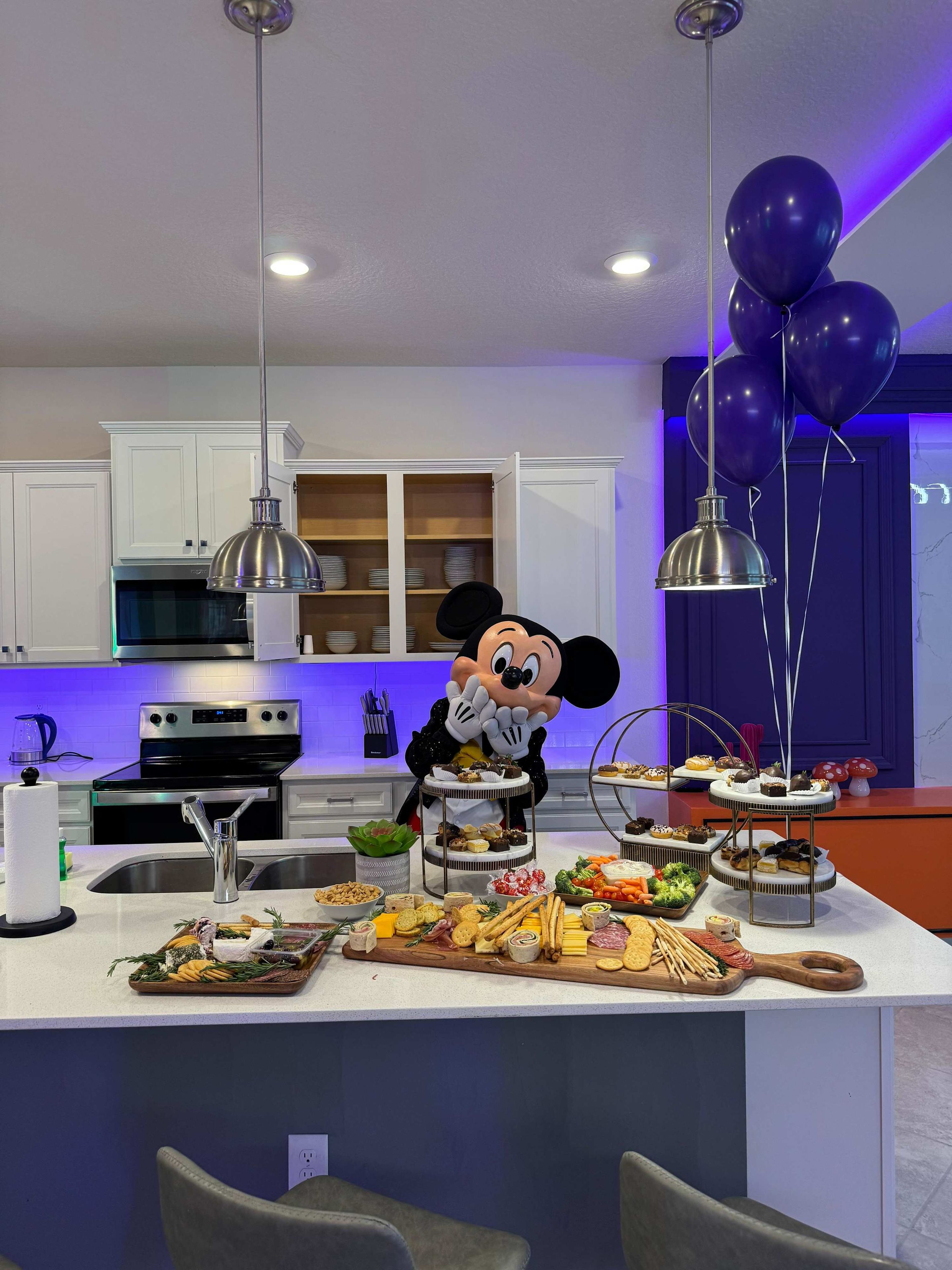 A modern kitchen with white cabinets, stainless steel appliances, and a central island with food displays.