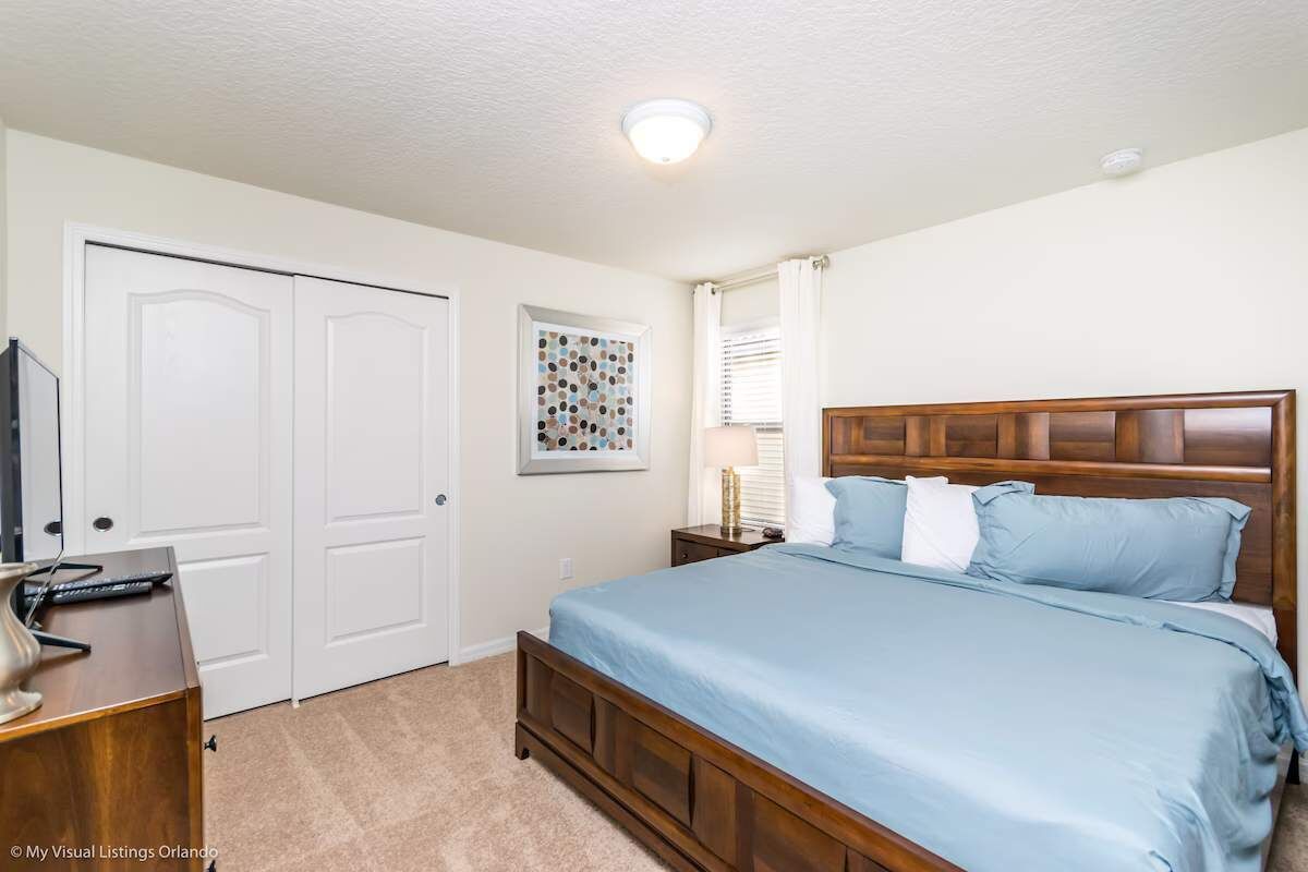 A bedroom with a wooden bed, a desk, and a white door.