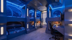 A room with bunk beds, a desk, and a chair, featuring a futuristic design with blue lighting and space-themed decor. - Luxurious Windsor Cay Retreat With Theater & Pool (Clermont)