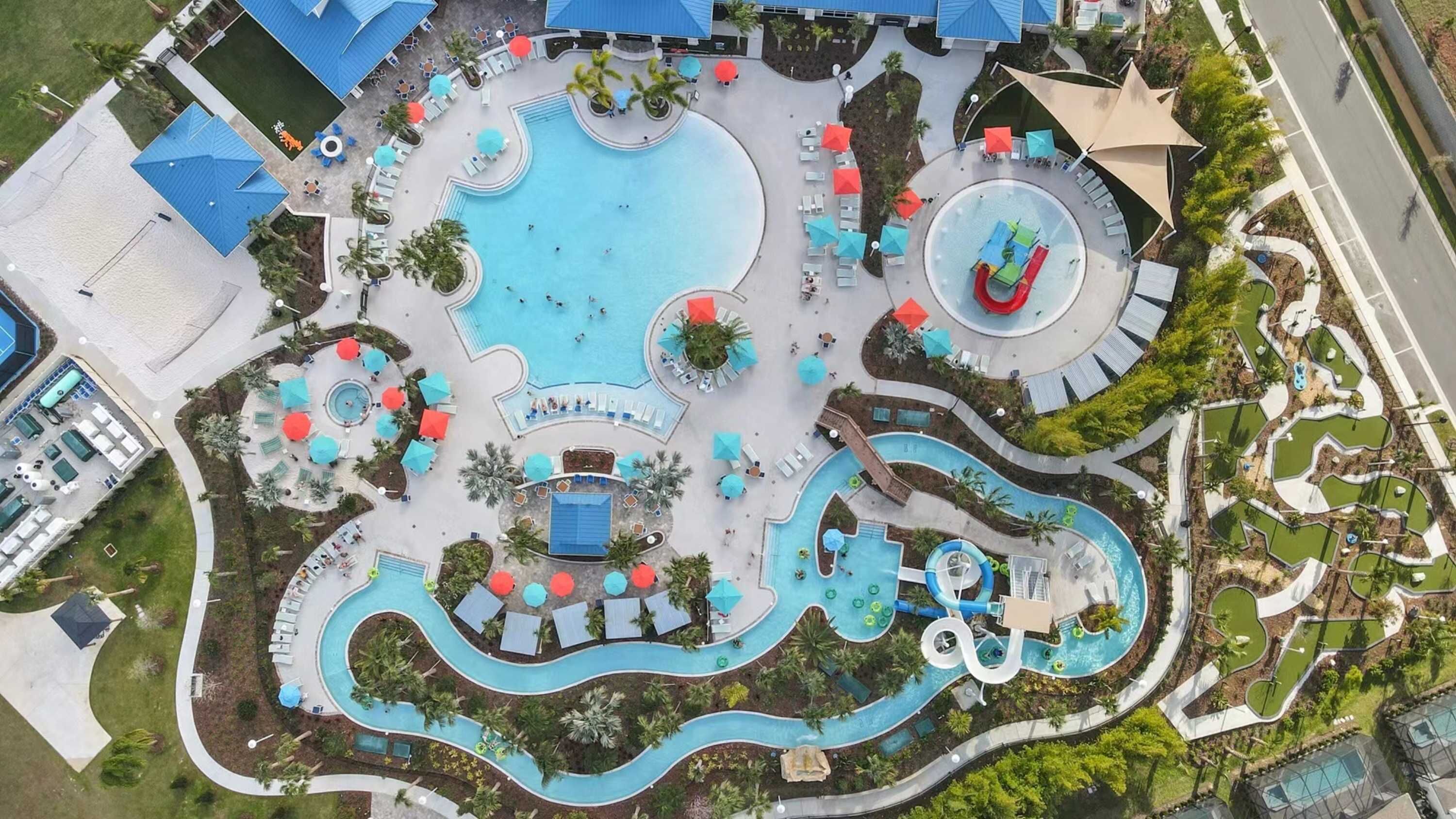 An aerial view of a resort with multiple swimming pools, sun loungers, and a water slide.