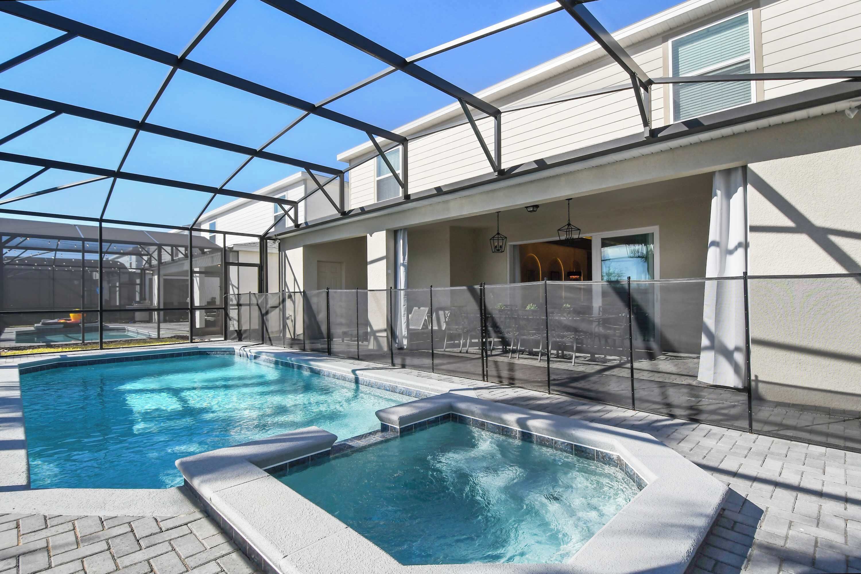 An indoor swimming pool with a glass ceiling, surrounded by a white building with a patio area.