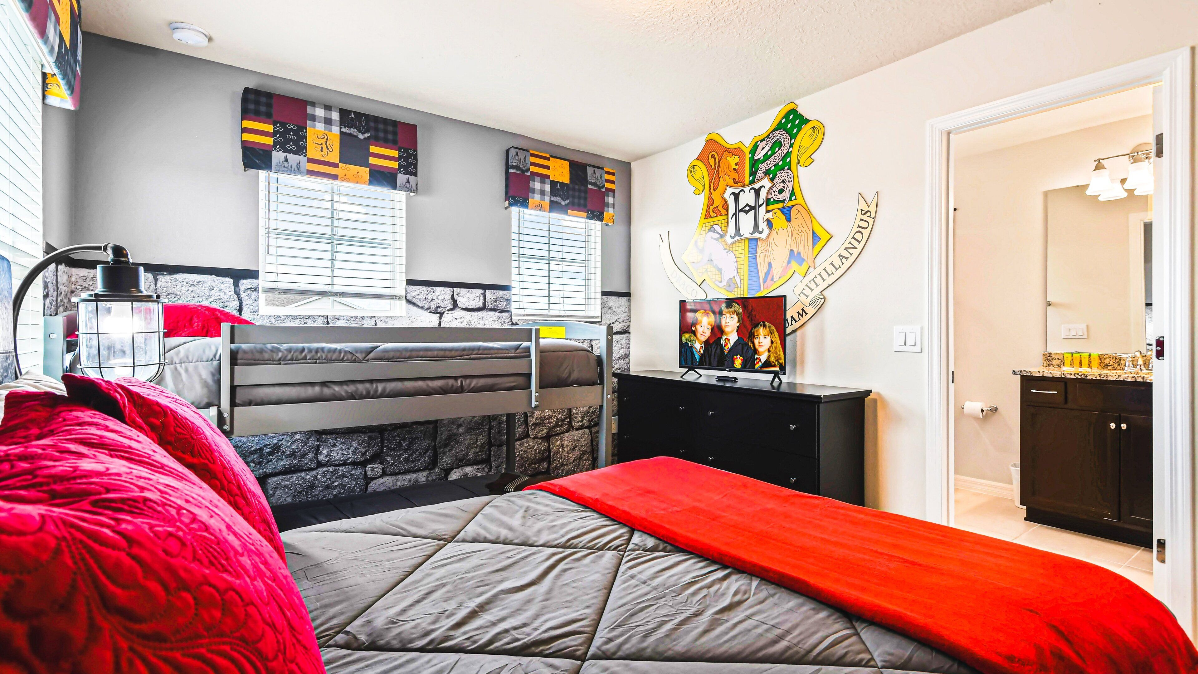 A bedroom with a bunk bed, a desk with a computer, a wall with a Harry Potter poster, and a window with blinds.