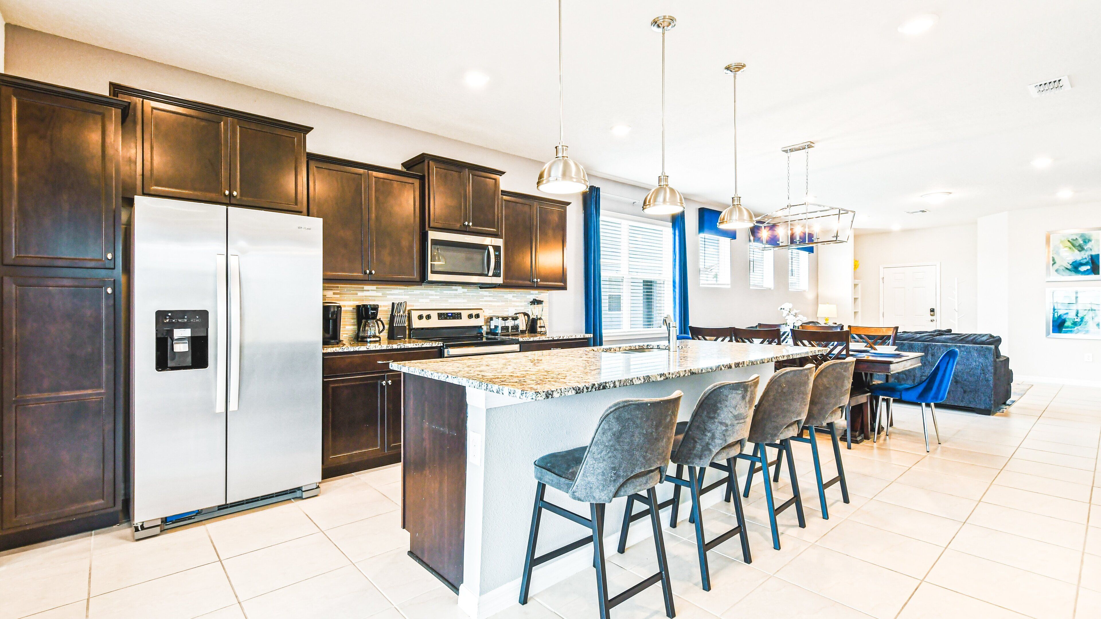 A modern kitchen with dark wood cabinets, stainless steel appliances, and a central island with bar stools.