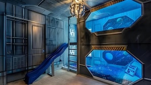 Een kamer met een glijbaan, zeshoekige ramen met een ruimte thema uitzicht en een sterrenhemel in het interieur.