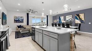 Een moderne keuken met een centraal eiland, grijze kastjes en hanglampen.