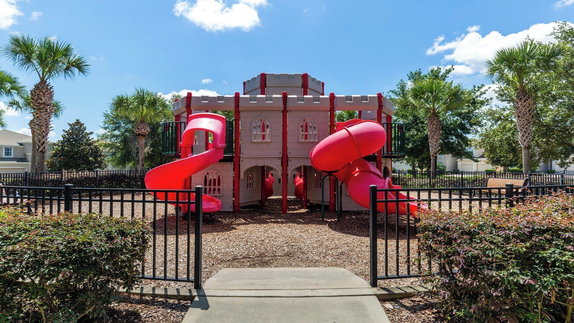 A castle-themed playground with two red slides and a central tower.