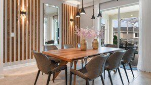 Un espace repas moderne avec une table en bois, six chaises et deux vases ornés de fleurs.