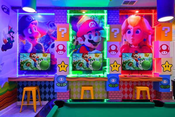 A brightly lit room with Mario and Luigi characters, neon lights, and multiple screens displaying video games. - Epic Family Getaway: Themed Villa Near Disney ! (Kissimmee)