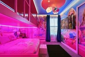 A brightly lit room with a bed, a small seating area, and a mural on the wall. - Epic Family Getaway: Themed Villa Near Disney ! (Kissimmee)