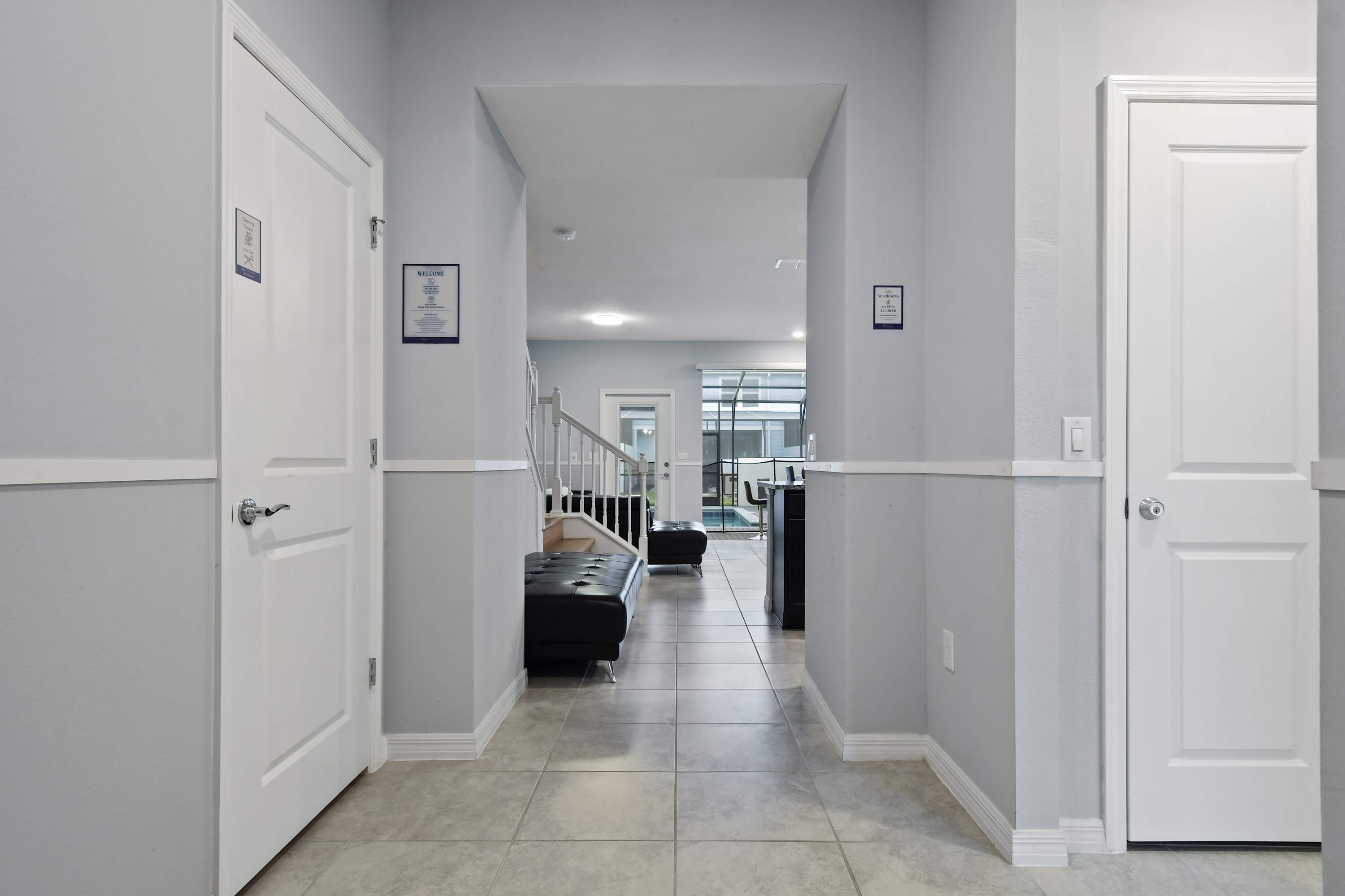 A hallway with white doors, a black bench, and a staircase leading to another floor.