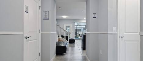 A hallway with white doors, a black bench, and a staircase leading to another floor.