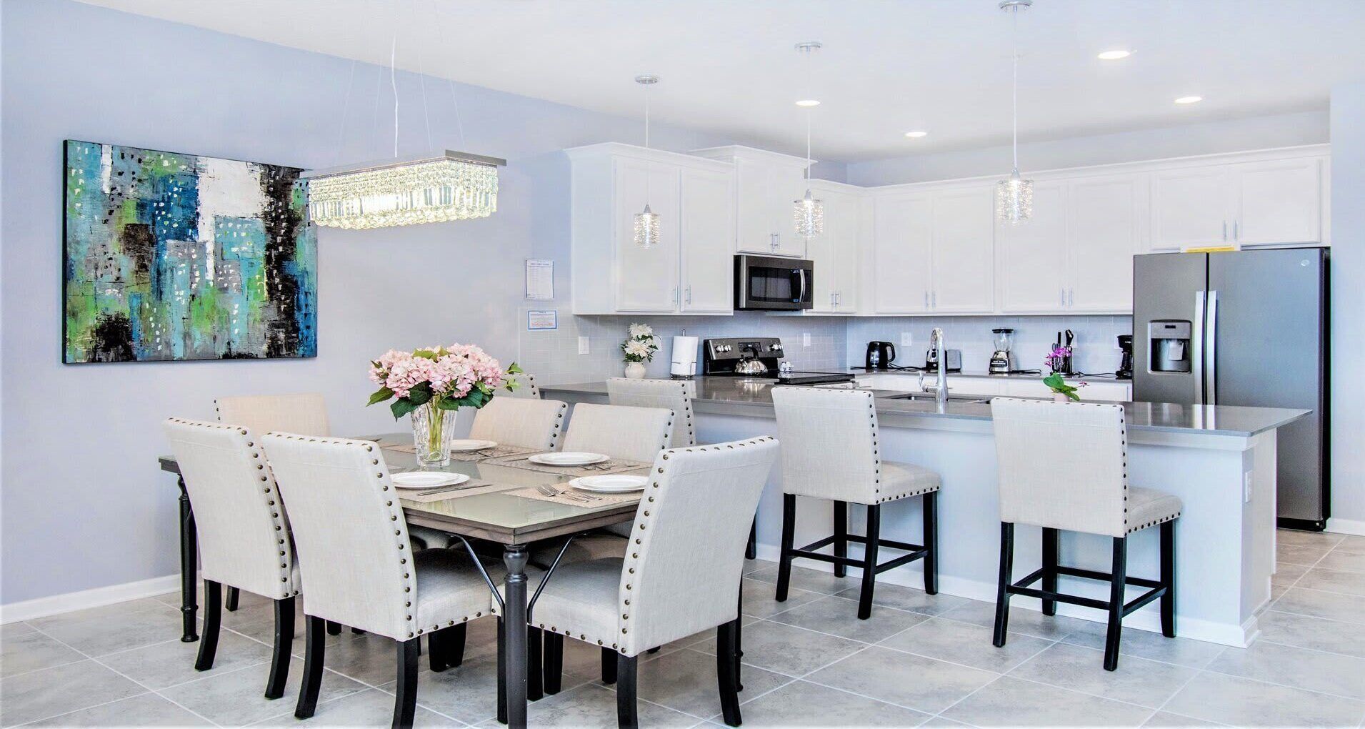 A modern kitchen with white cabinets, a central island, and pendant lighting.