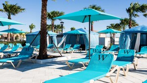 A poolside area with lounge chairs and umbrellas, surrounded by palm trees. - Ultimate 8BR Family Fun in Resort Near Disney! (Kissimmee)