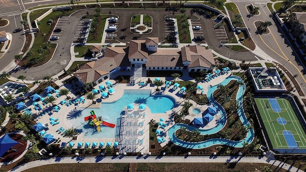 An aerial view of a resort with a swimming pool, sun loungers, a water slide, and a basketball court. - Ultimate 8BR Family Fun in Resort Near Disney! (Kissimmee)
