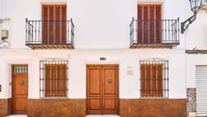 A building with a wooden door, a balcony with a metal railing, and a stone wall. - 'Animas 1' Apartment with Balcony, Wi-Fi, and Air Conditioning (Nerja)