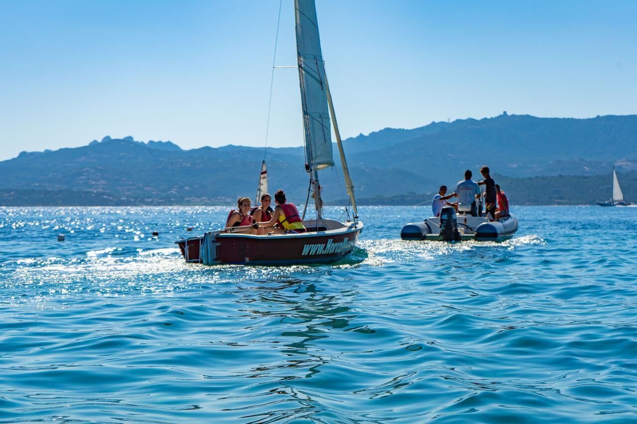 A sailboat with people on board and another boat nearby.
