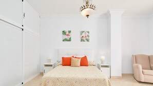A bedroom with a bed, nightstands, a chair, and wall art. - Duplex Home by Balcón de Europa with 2 Large Sunny Terraces and Barbecue (Nerja)