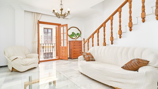 A living room with a sofa, armchair, wooden staircase, and a chandelier. - Duplex Home by Balcón de Europa with 2 Large Sunny Terraces and Barbecue (Nerja)