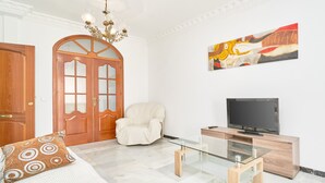 A room with a bed, a glass coffee table, a TV, a chair, and a door. - Duplex Home by Balcón de Europa with 2 Large Sunny Terraces and Barbecue (Nerja)