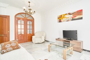 A room with a bed, a glass coffee table, a TV, a chair, and a door. - Duplex Home Next to Balcón de Europa with 2 Large Sunny Terraces and Barbecue (Nerja)