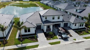 Un barrio residencial con varias casas, un lago pequeño y un camino pavimentado.