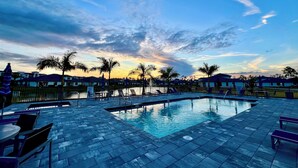 Una piscina con sillas de descanso y vistas al atardecer.
