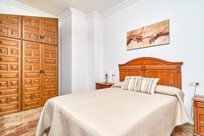Un dormitorio con una cama grande, un armario de madera y un cuadro en la pared.
