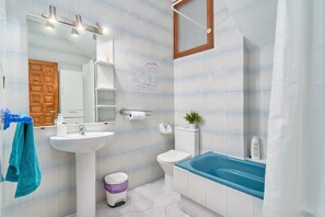 Un baño con lavamanos, inodoro, bañera y espejo.