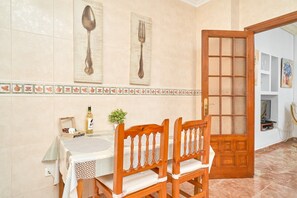 Un comedor con una mesa, sillas, un menú pegado a la pared y una puerta con un panel de vidrio esmerilado.