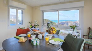 A dining area with a table set for breakfast, a view of the city, and a large window.