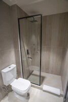 Un baño moderno con ducha de vidrio, inodoro y perchero para toallas.