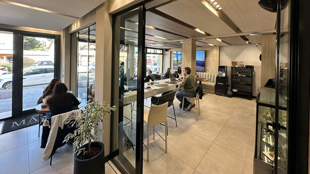 A modern cafe with large windows, seating areas, and a coffee machine. - MABRA SUITES (El Calafate)