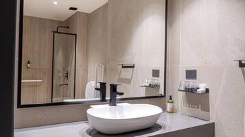 A modern bathroom with a large mirror, a white vessel sink, and a shower area.