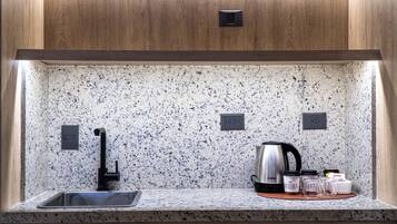 Eine Küche mit Granit-Arbeitsplatten, einer Edelstahl-Spüle, einem Wasserkocher und einer Kaffeemaschine.