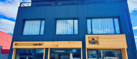 A modern building with a coffee bar and a MABRA Suites sign.