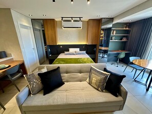 Une chambre d’hôtel moderne équipée d’un canapé, d’un lit, d’un bureau et d’un coin repas.