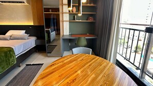 A modern hotel room with a bed, desk, chair, and a round wooden table. - New and elegant studio in Campo Grande/MS (Centro Campo Grande)