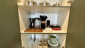 A kitchen with shelves holding pots, a coffee maker, and utensils. - New and elegant studio in Campo Grande/MS (Centro Campo Grande)