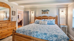 Une chambre à coucher avec un grand lit, une tête de lit en bois, deux tables de chevet avec des lampes, une commode et un miroir.