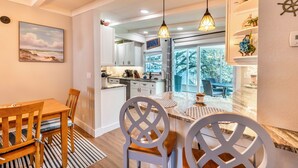 Une cuisine moderne avec des meubles blancs, un coin repas avec des chaises à rayures et des luminaires suspendus.